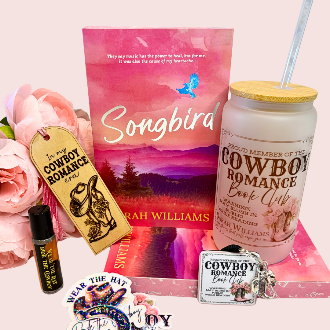 Collection of 'Songbird' book box with tumbler, and related merchandise on a pink surface.