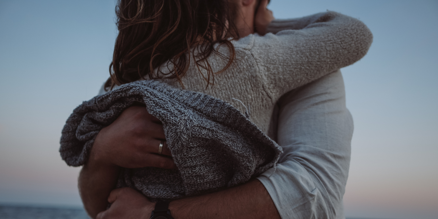 Two people embracing on a beach at sunset