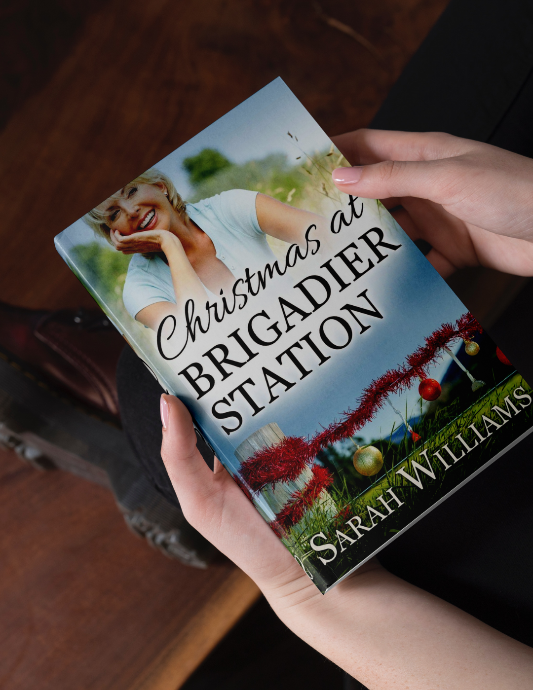 Book titled 'Christmas at Brigadier Station' by Sarah Williams held by a person.