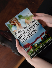 Book titled 'Christmas at Brigadier Station' by Sarah Williams held by a person.