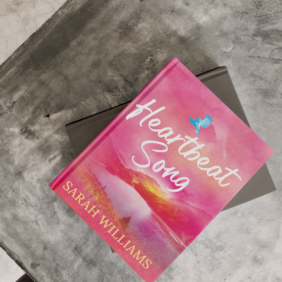 Book titled 'Heartbeat Song' by Sarah Williams on a concrete surface