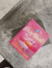 Book titled 'Heartbeat Song' by Sarah Williams on a concrete surface