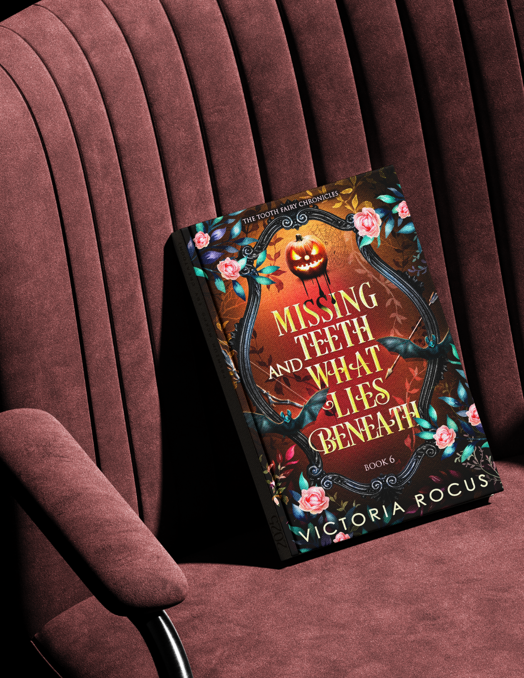 Book titled 'Missing Teeth and What Lies Beneath' by Victoria Rocus on a maroon chair