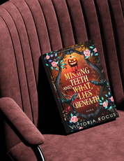Book titled 'Missing Teeth and What Lies Beneath' by Victoria Rocus on a maroon chair