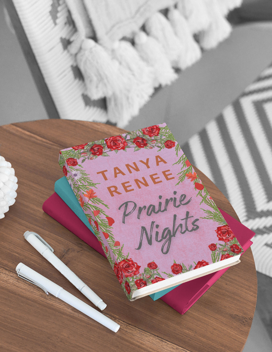Book titled 'Prairie Nights' by Tanya Renee on a wooden table with two pens.