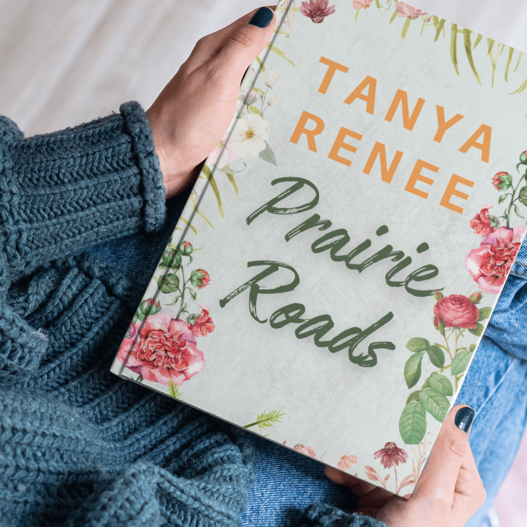 Book titled 'Prairie Roads' by Tanya Renee held by a person wearing a blue sweater.