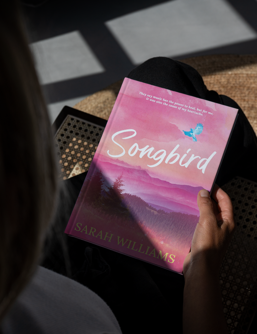 Book titled 'Songbird' by Sarah Williams held by a person.