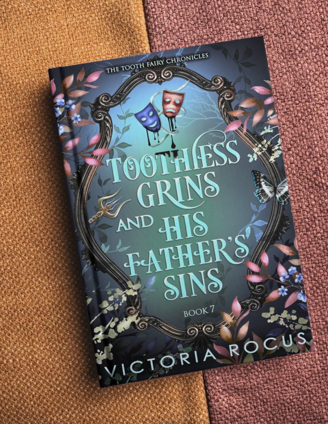 Book titled 'Toothless Grins and His Father's Sins' by Victoria Rocus on a textured surface