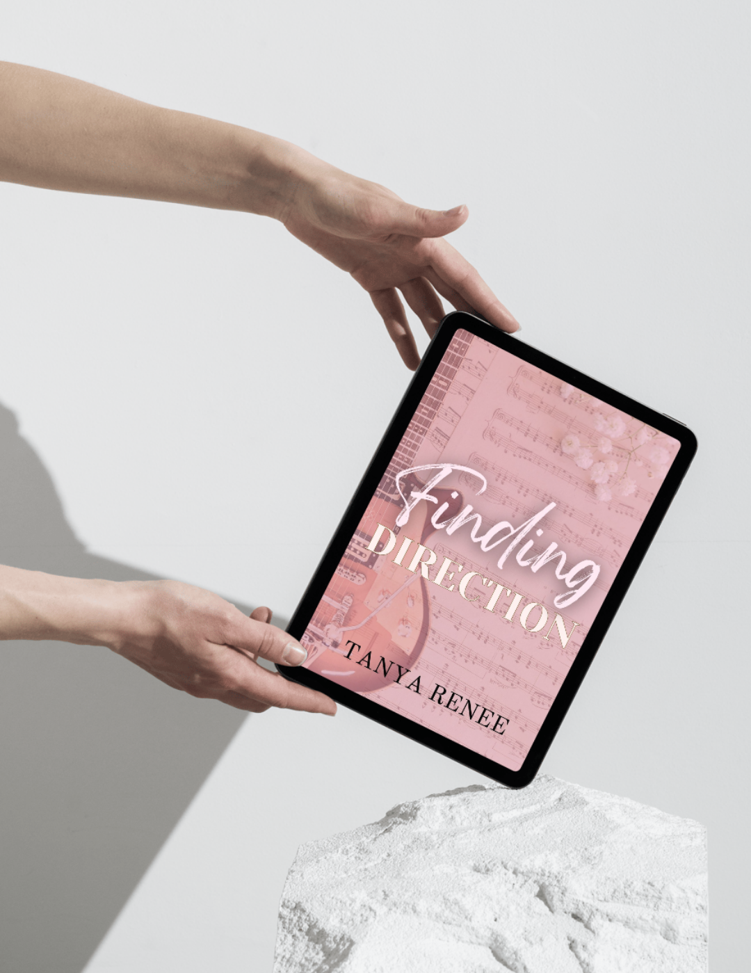 Person holding a tablet with 'Finding Direction' by Tanya Renee on a light background