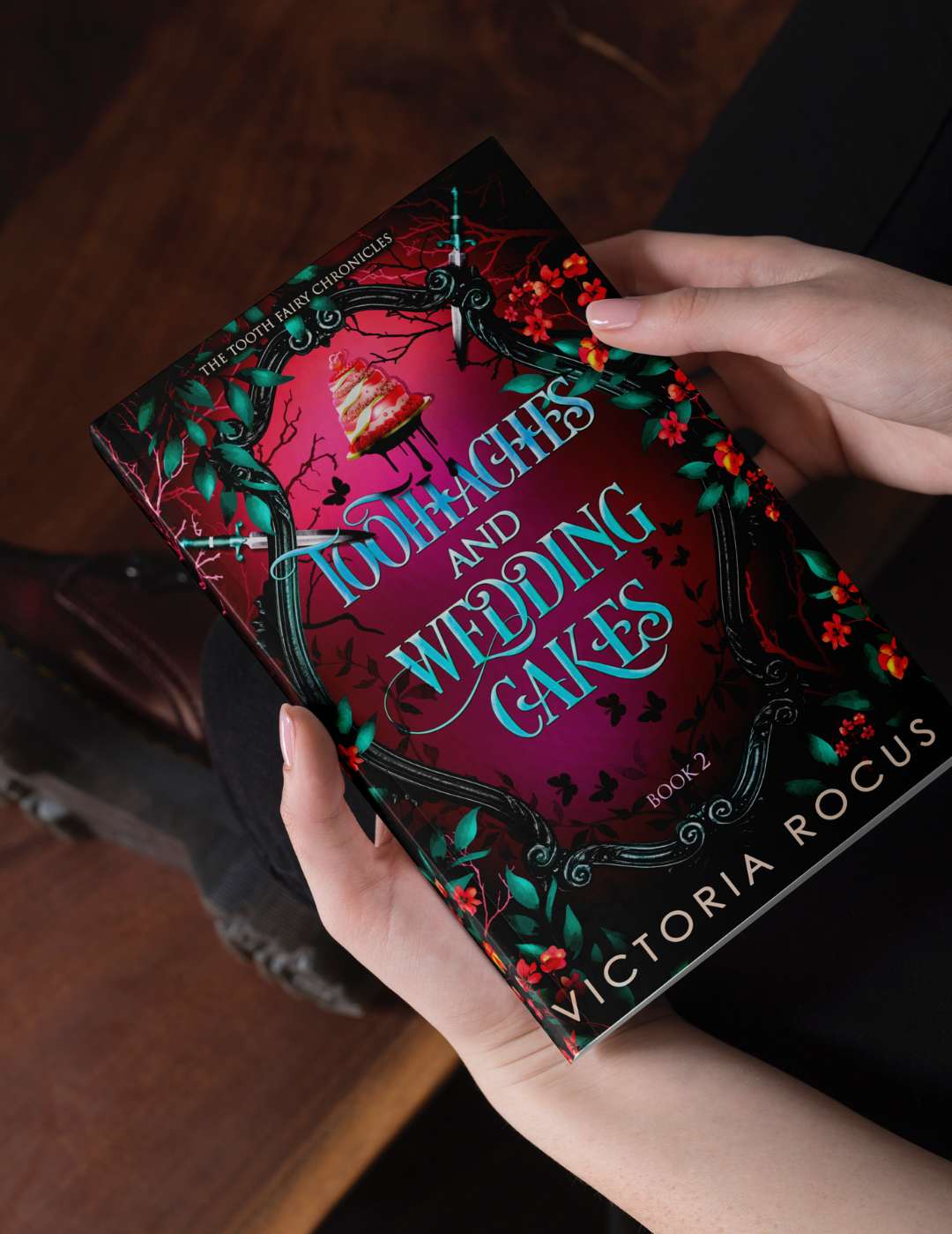 Book titled 'Toothaches and Wedding Cakes' by Victoria Rocus held by a person.