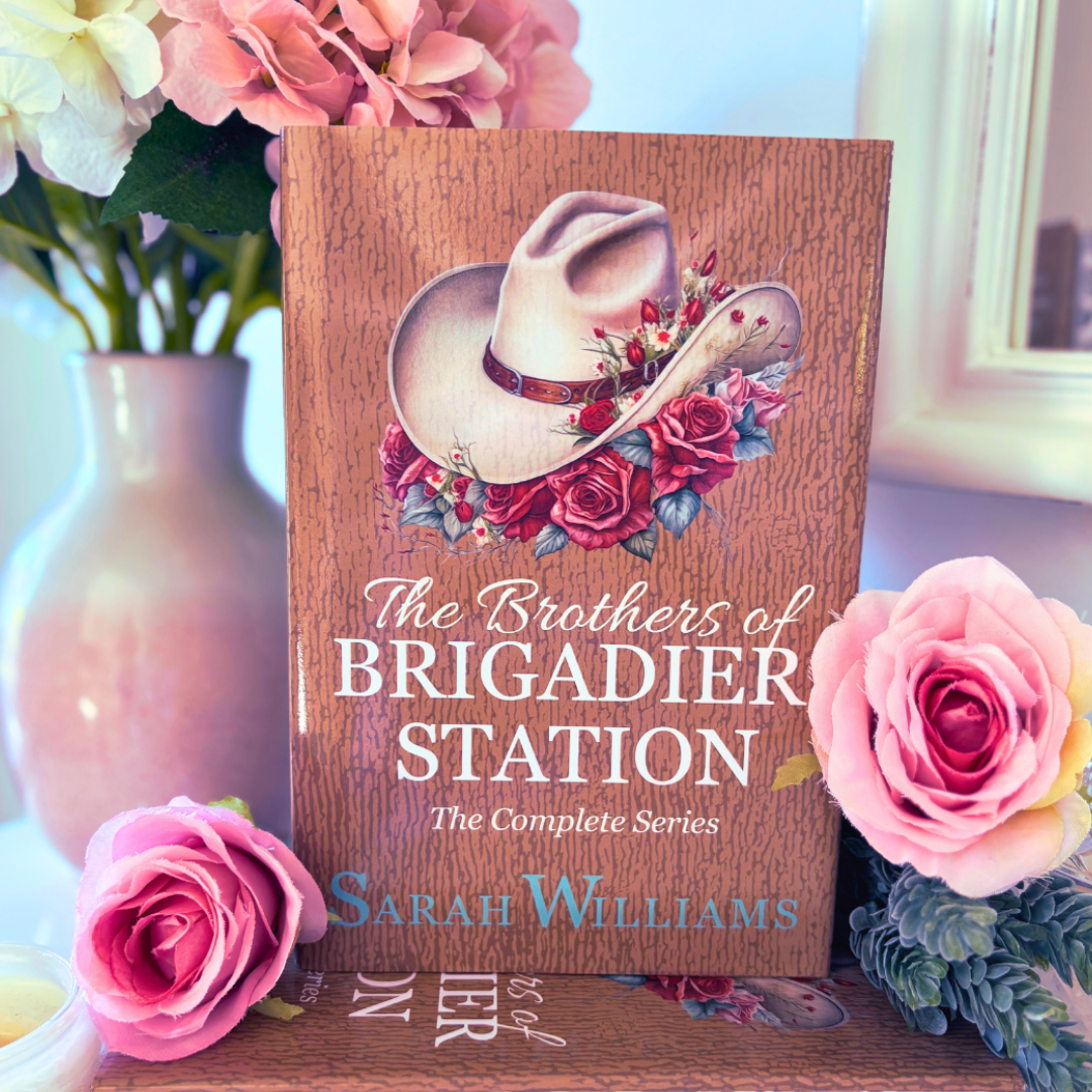 Book titled 'The Brothers of Brigadier Station' by Sarah Williams with floral design on a decorative stand, surrounded by flowers.