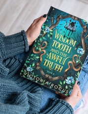 Book titled 'Wisdom Tooth and the Awful Truth' by Victoria Rocus held by a person wearing a blue sweater.